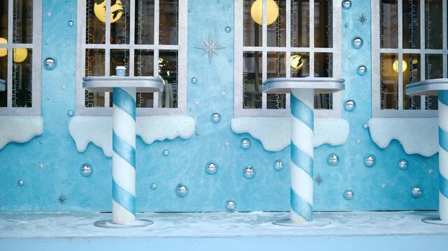Whimsical blue candy factory plant facade with snow, striped candy cane poles