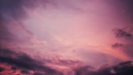 Fototapeta premium A wide view of a sky with soft layered clouds iluminated by warm sunset hues