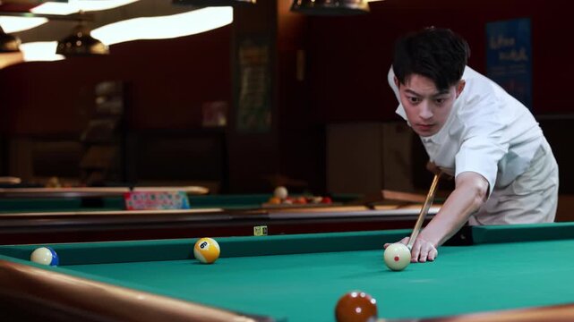 Young pool player hit the white cue ball with the cue to drives brown american pool ball into the pocket of green billiard table with smooth precise, sport activity at home indoors, strategic gameplay