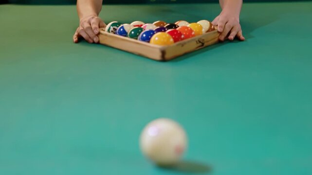 Coloured billiard balls arranged by wooden rack triangle on green felt pool table ready to play new game of snooker, white cue ball waits ready for opening start first break shot, leisure strategy