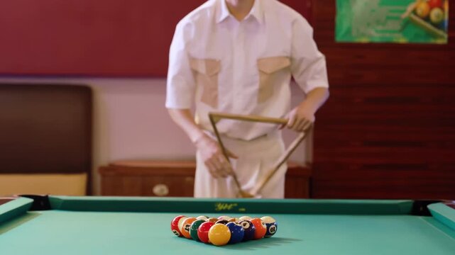 Coloured billiard balls setted up wooden rack triangle on felt pool table ready to play new game of snooker by player, white cue ball waits ready for opening start first break shot, leisure strategy