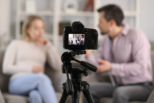 Male journalist with microphone having an interview with woman on camera screen in studio, closeup