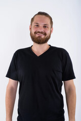 Obraz premium Studio portrait of a friendly young caucasian man with a beard and hair bun wearing a black v-neck shirt. He is smiling at the camera against a white background. Modern male lifestyle concept.