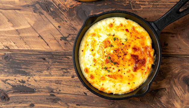 Provoleta Cheese in Cast Iron Skillet on Wooden Table