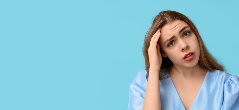 Thoughtful young woman trying to remember something on blue background with space for text