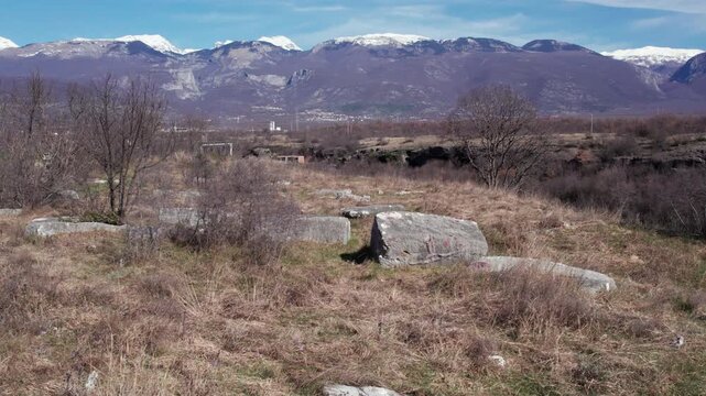 Wide landscape of medieval stecci tombstones in Herzegovina with mountains in the background, showcasing cultural heritage and historic burial grounds.