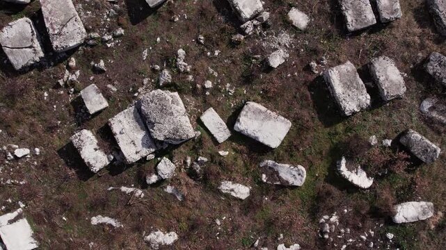Aerial shot starting on a single stecak tombstone and revealing a wider medieval necropolis in Herzegovina, showing historic burial landscape.