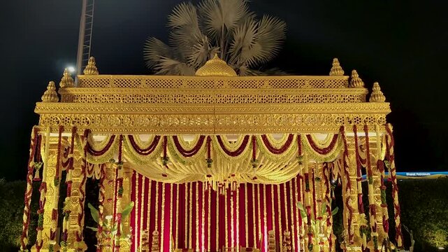 Indian wedding mandap with intricate gold decor and vibrant floral arrangements. Elegant traditional wedding setting.