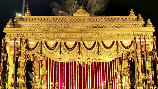 Indian wedding mandap decorated with intricate gold designs and vibrant floral arrangements. Perfect for wedding, cultural, and traditional ceremony footage.