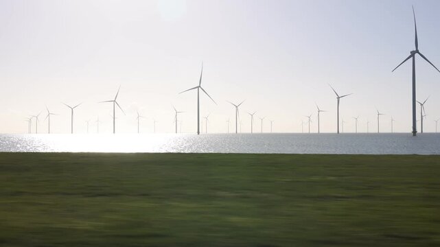 Sunny grassland view toward wind farm beside the sea