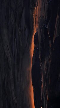 Vertical Screen: Yosemite National Park Firefall phenomenon with glowing orange waterfall cascading down dark granite cliff face at sunset, creating stunning natural light display