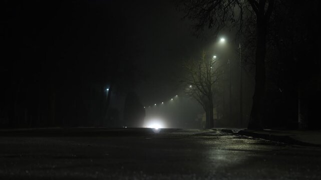 Eerie suburban street at night with soft streetlights and car reflections on wet