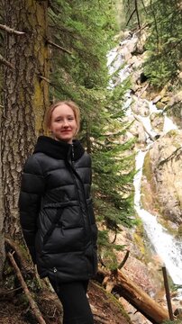 A girl in the mountains near a waterfall in early spring.
