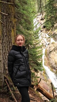 A girl in the mountains near a waterfall in early spring.