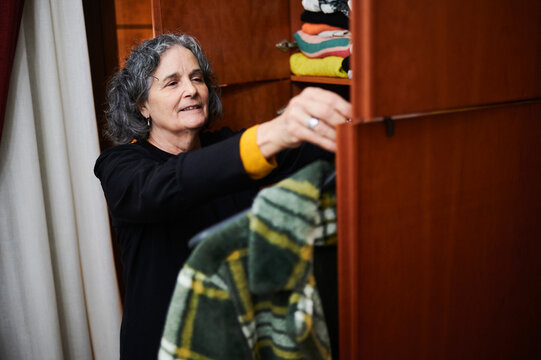 Senior woman choosing clothes from her closet