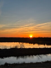 Obraz premium A stunning sunset where the sky is ablaze over the Himmelmoor. A lake can be seen in the background.