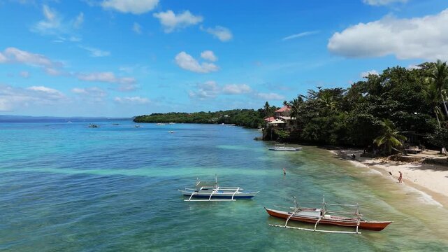 A drone ascends and pans left over Panglao Beach and shallow water in Panglao, Bohol