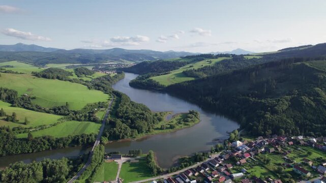 Aerial view of Orava region landscape in Slovakia, river reservoir winding through green hills and rural village.