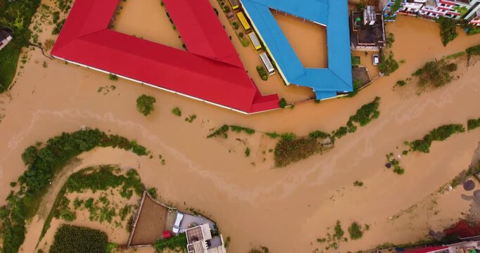 Top-down drone shot of heavy monsoon flooding in Banepa with river overflow submerging settlements, trucks, vehicles and green agricultural land near Kathmandu Nepal.