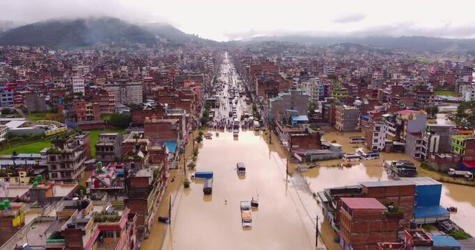 Drone shot of floodwaters in Banepa disrupting the highway with cargo trucks stranded and buildings submerged after heavy monsoon rainfall in Nepal.