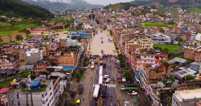 Drone shot of heavy traffic on Araniko Highway in Banepa caused by monsoon flooding with submerged buildings and vehicles leading to highway blockade in Nepal.