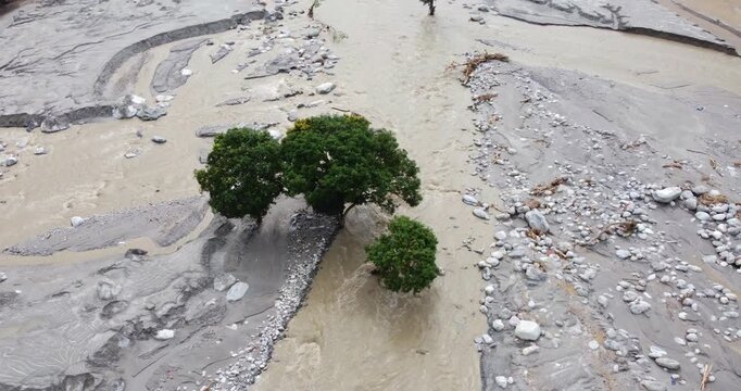 Drone shot of resilient trees standing within the Melamchi River after flood damage, surrounded by debris and altered river landscape in Sindhupalchowk Nepal.