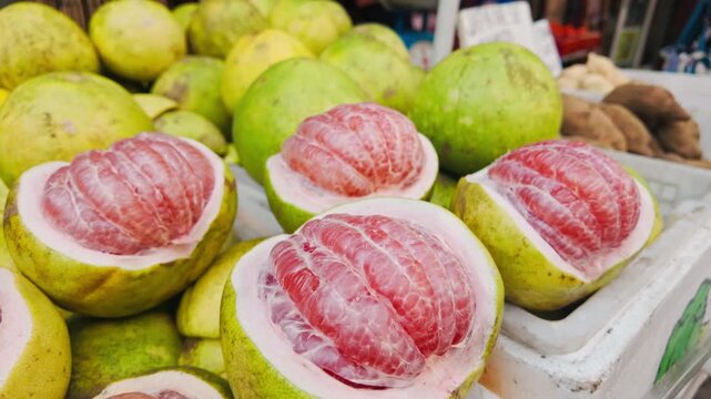 Fresh pomelos with pink flesh displayed at market stall in Manila Chinatown