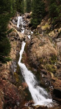 Mountain waterfall in a wild forest in early spring.	