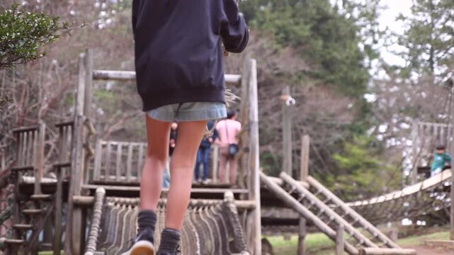 Slow motion of a boy playing on a zip line or rope swing at an outdoor adventure park, rear view.
