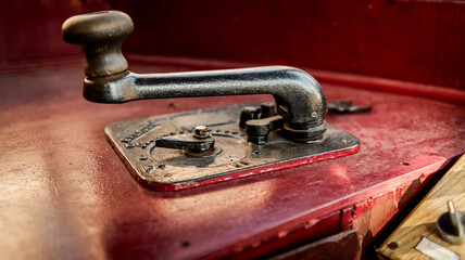 Close-up of an antique telegraph key with a worn metal lever on a red surface © shine.graphics