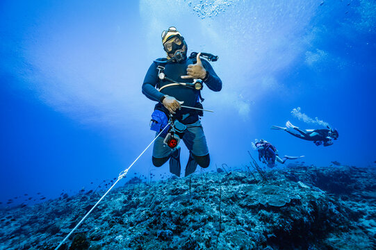 diver using a reef hook in strong current in the Maldives