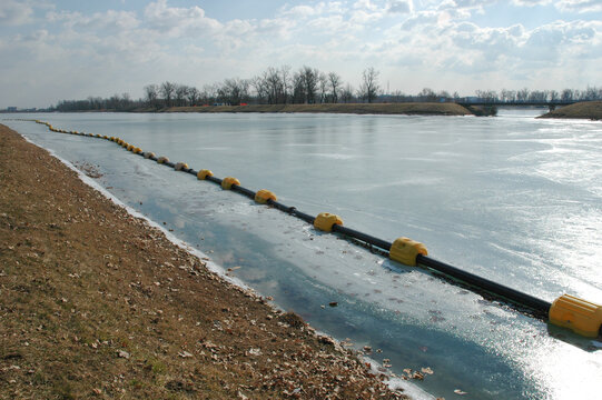 A long black floating pipeline with yellow buoys stretches across the frozen surface of Jarun Lake in Zagreb during winter