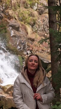 A woman against the backdrop of a mountain waterfall.