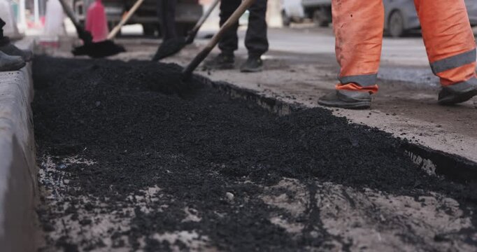 Workers repairing asphalt road on city street