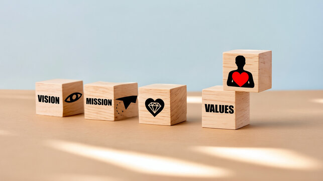 A set of wooden blocks with vision, mission, and values concepts on a light blue background