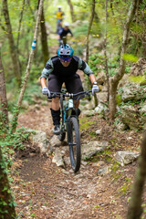 Fototapeta premium Experienced cyclist riding a mountain bike on a rocky forest trail in full protective gear