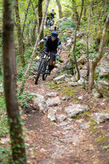 Fototapeta premium Man mountain biking on rocky forest trail wearing helmet and action camera