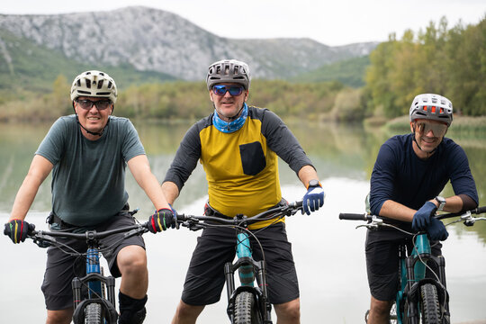 Three friends mountain biking by a lake enjoying outdoor adventure and fitness together