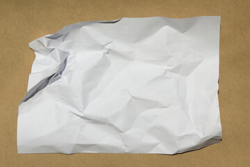 Obraz premium Crumpled paper lying on a brown background.
