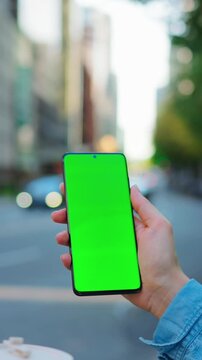 Woman is standing on the street and using smartphone with green screen