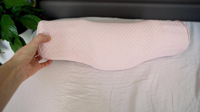 Point of view touching ergonomic orthopedic pillow on bed. Feeling soft memory foam texture, checking comfort and shape for cervical support, neck alignment and better sleep at home.