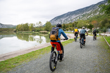 Obraz premium Group mountain biking along a lakeside trail with cyclists enjoying outdoor adventure