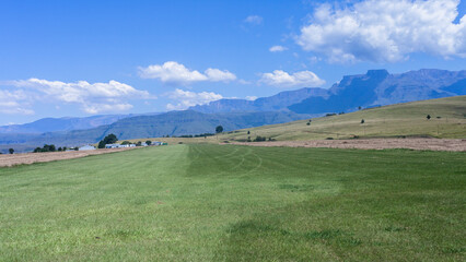 Fototapeta premium Flying grass airstrip for light aircraft planes airport runway layout in farming country scenic mountains with blue sky landscape.