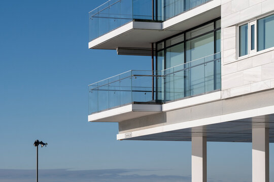 Modern coastal architecture building with glass balconies facing the horizon under open sky with minimal copyspace for serene lifestyle visuals