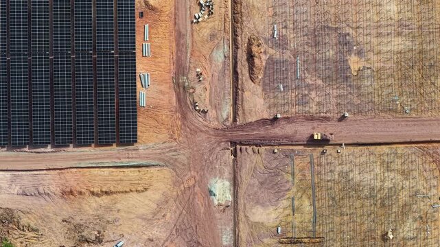 Drone aerial view showing solar panel farm under construction in arid landscape