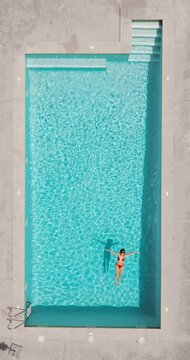 Top down view of a woman in redre swimsuit lying on her back in the pool.