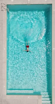 Aerial view as a man dives into the pool and swims. Slow motion