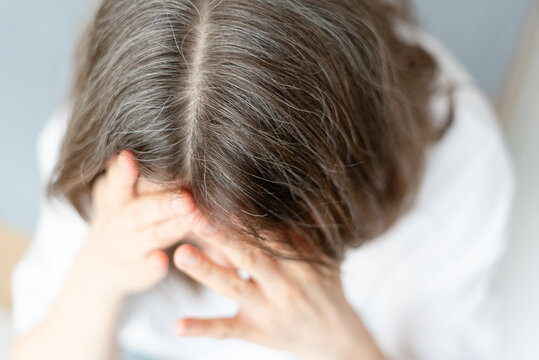 Close up view of gray hair linked to poor nutritional choices over many years. The mature adult examines how unhealthy eating affected her silver strands. Mother regrets past food decisions deeply.
