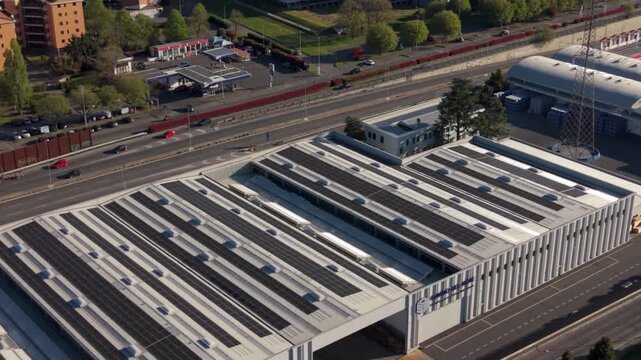 Aerial perspective of a modern warehouse in Peschiera Borromeo, Italy. Solar panels on the roof convert sunlight into renewable energy supporting sustainable logistics operations.