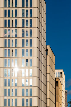 Modern architecture facade on a tower with symmetry in windows and reflection creating geometry pattern against clear sky background